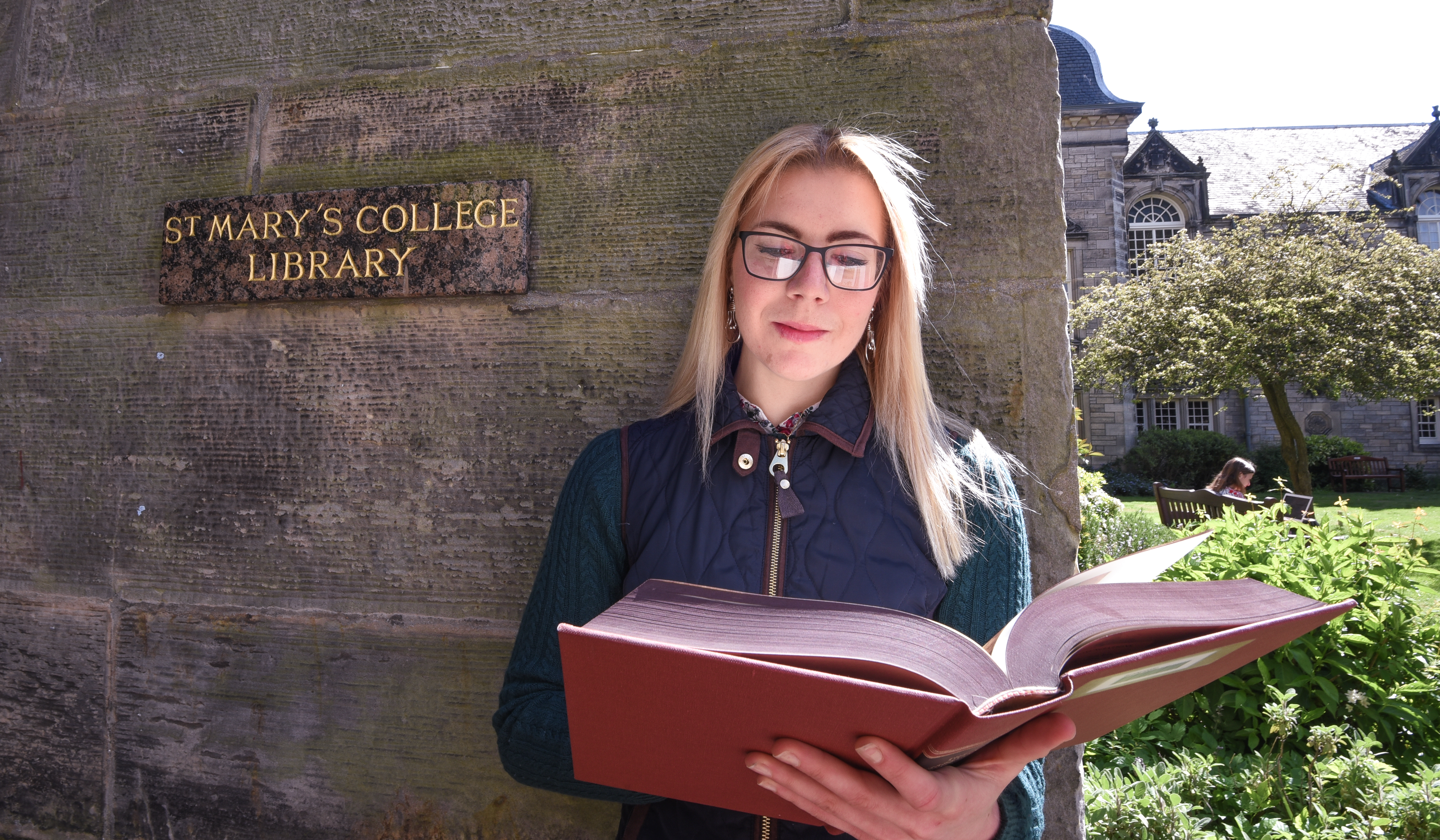 Student with a book, stood outside of St Mary's College Library